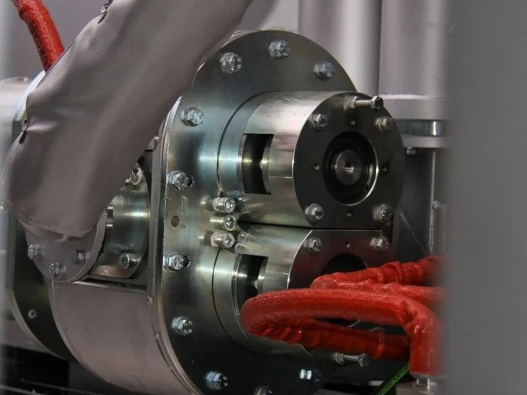Close-up of a thermoplastic pump flange with oil-jacketed hoses on RME equipment